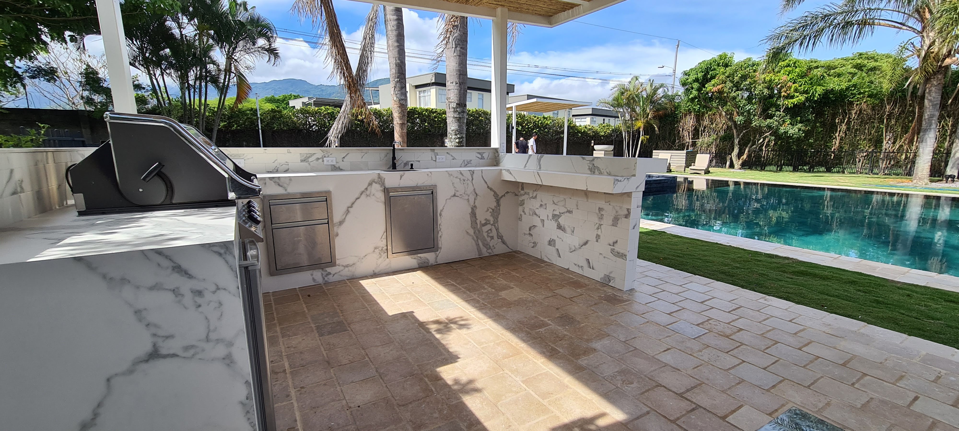 Cocina exterior revestida en piedra junto a piscina